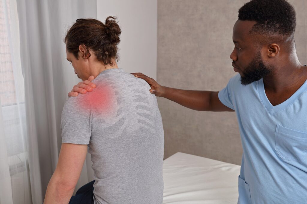 A man holding his back due to pain and doctor taking care | Hudson Premier PT & Sports in Union City, Jersey City, NJ