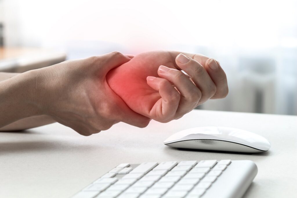A Man holding his wrist due to pain while working | Hudson Premier PT & Sports in Union City, Jersey City, NJ