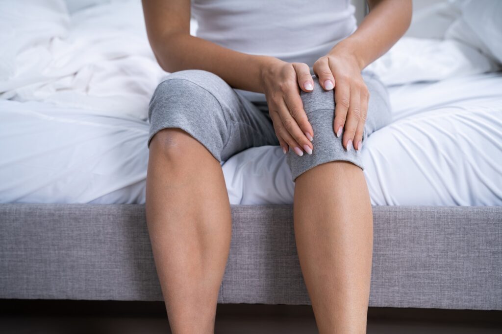 A Woman Suffering From Knee Pain Sitting on bed | Hudson Premier PT & Sports in Union City, Jersey City, NJ
